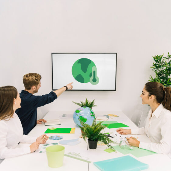 Eine Gruppe von Menschen in einem Meeting, die über den Klimawandel diskutieren, mit einem Globus und grünen Materialien auf dem Tisch.