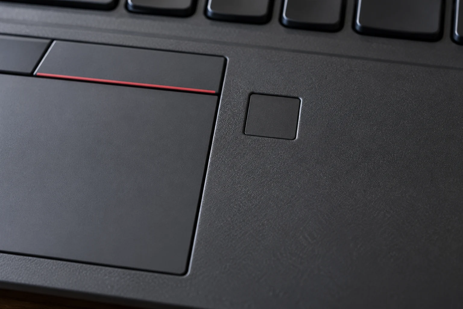 Nahaufnahme der Notebook-Handballenauflage mit Touchpad und einem kleinen quadratischen Sensorfeld daneben.